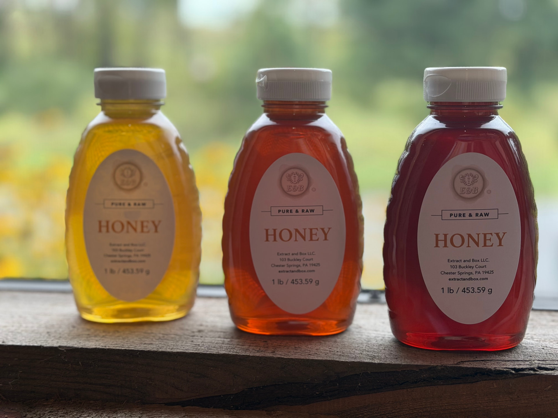 Three bottles of local raw honey on a wooden ledge